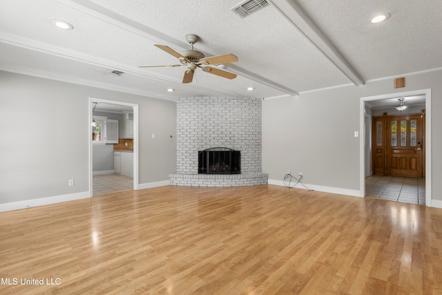 unfurnished living room with beam ceiling, ceiling fan, light hardwood / wood-style flooring, a textured ceiling, and a fireplace