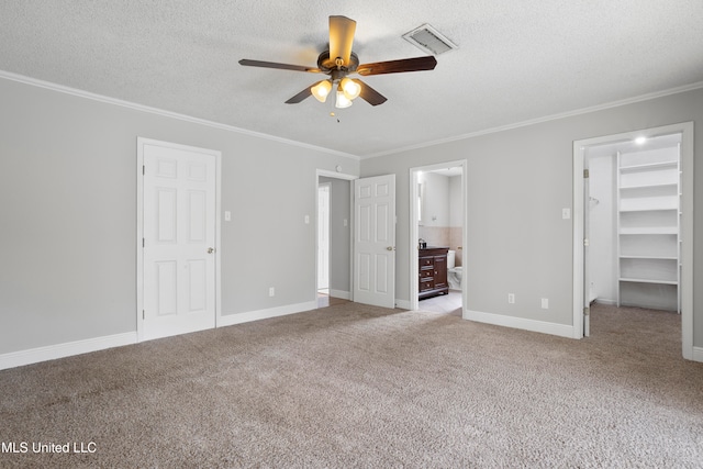 unfurnished bedroom with a walk in closet, ceiling fan, ensuite bath, and light colored carpet