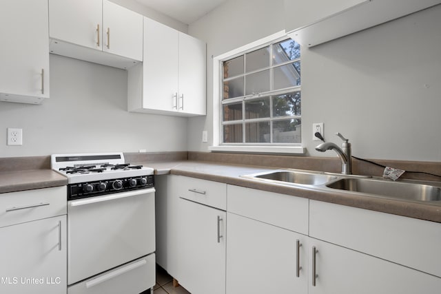 kitchen with tile patterned floors, sink, white cabinets, and white range