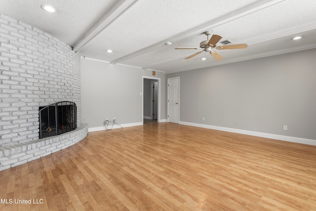 unfurnished living room featuring beam ceiling, a textured ceiling, and light hardwood / wood-style floors