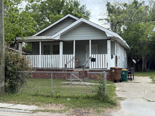 bungalow-style house with a porch and a fenced front yard