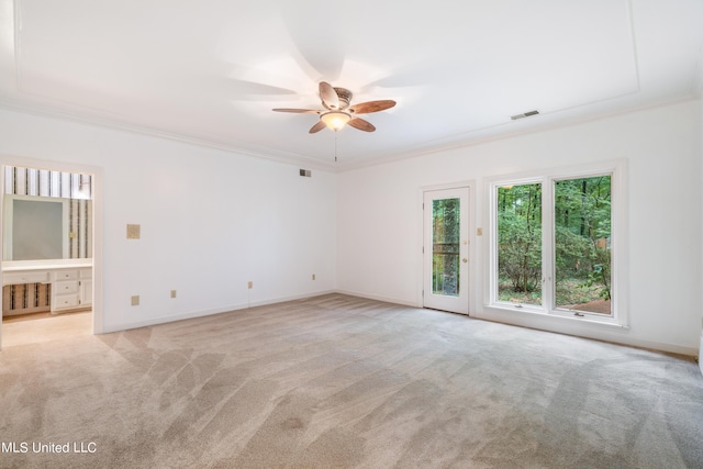 unfurnished room with ceiling fan, light colored carpet, and crown molding