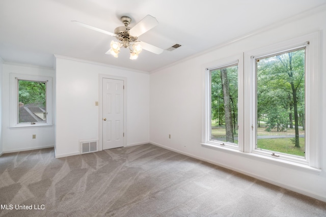 carpeted empty room with plenty of natural light, ceiling fan, and crown molding