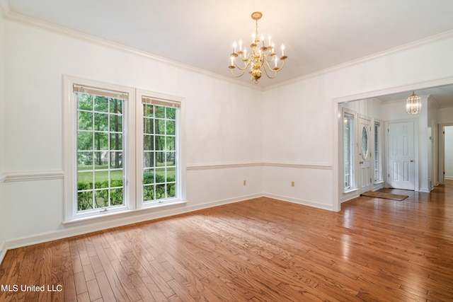 spare room featuring hardwood / wood-style floors, a notable chandelier, and ornamental molding