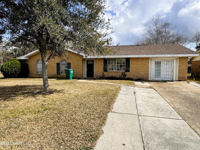 ranch-style home with brick siding, a front lawn, and french doors