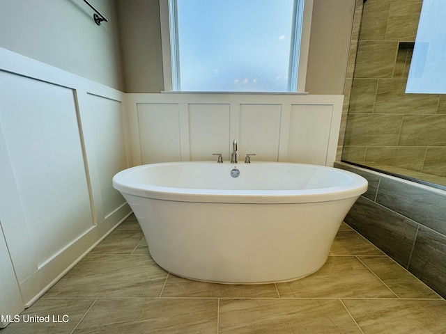 3919 Mcelroy Farms Dr, Olive Branch, MS 38654 - bathroom with a decorative wall, a freestanding tub, tile patterned floors, and wainscoting