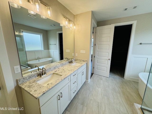 3919 Mcelroy Farms Dr, Olive Branch, MS 38654 - full bathroom with double vanity, a wainscoted wall, a soaking tub, and a decorative wall