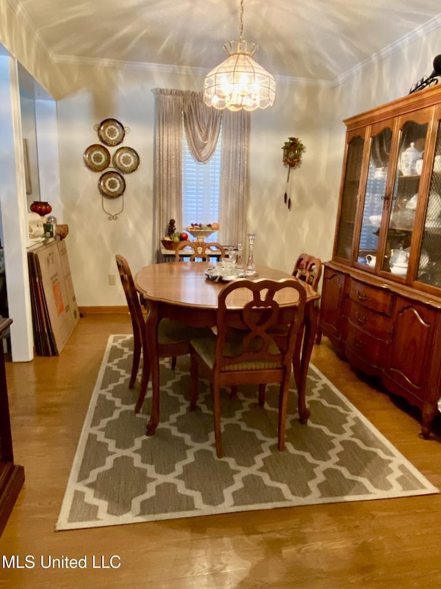 dining space featuring wood finished floors and crown molding