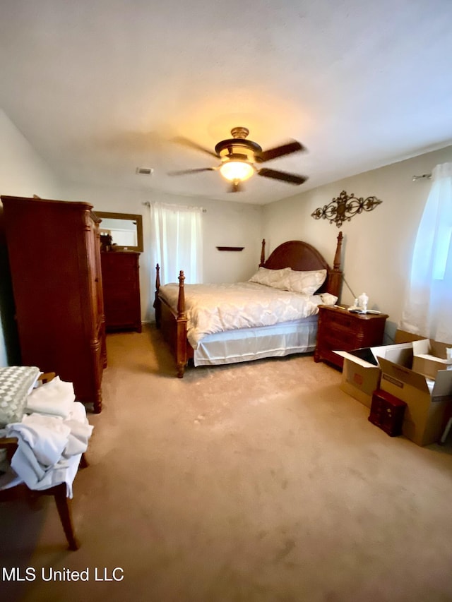 bedroom with visible vents, light colored carpet, and a ceiling fan