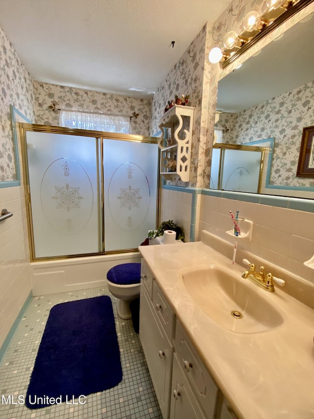 bathroom featuring wallpapered walls, shower / bath combination with glass door, tile walls, wainscoting, and tile patterned flooring