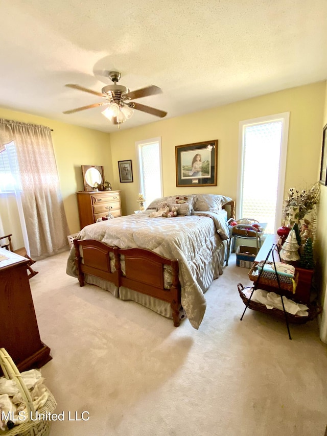 bedroom featuring a ceiling fan, a textured ceiling, and carpet flooring