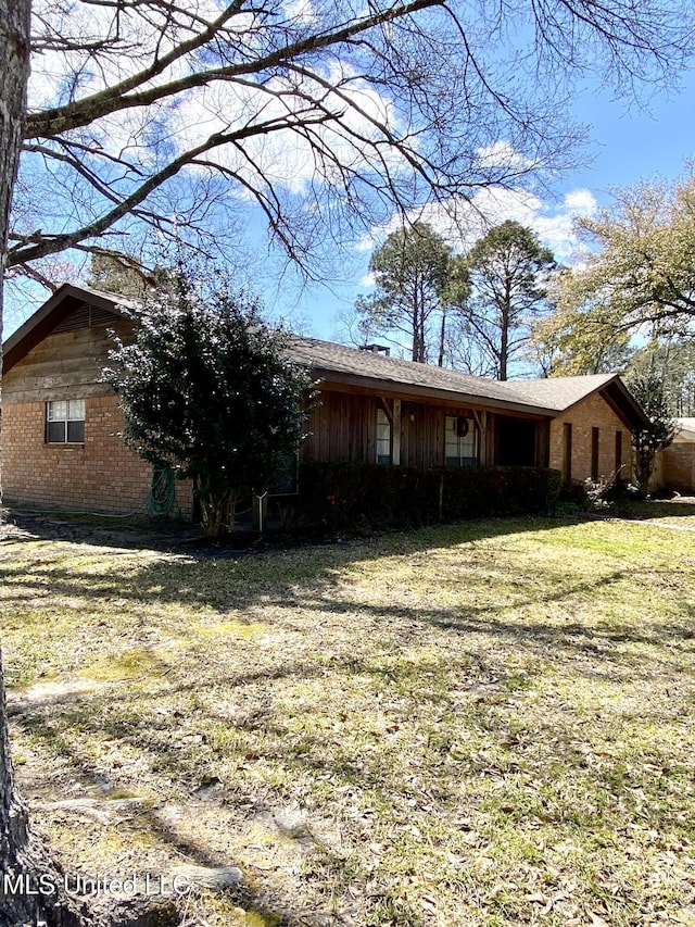 exterior space featuring a lawn and brick siding