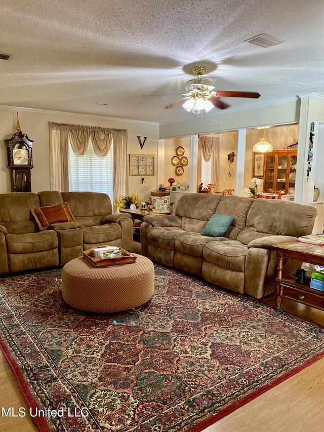 living room featuring visible vents, ornamental molding, a textured ceiling, and wood finished floors