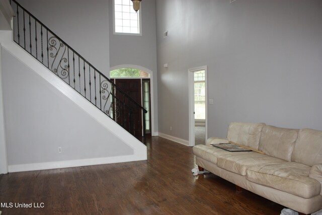 living room featuring dark hardwood / wood-style flooring, a towering ceiling, and plenty of natural light