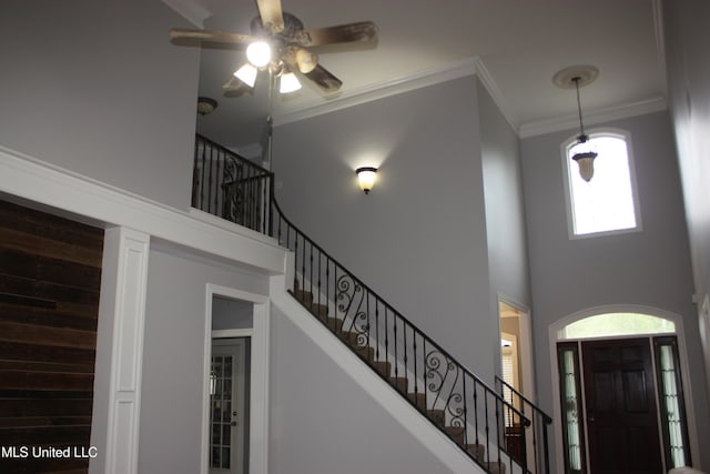 foyer entrance with a high ceiling, ceiling fan, and crown molding