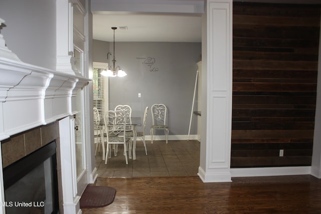 unfurnished dining area with a chandelier, a tile fireplace, and dark hardwood / wood-style floors