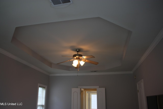 interior details featuring ceiling fan, a tray ceiling, and ornamental molding