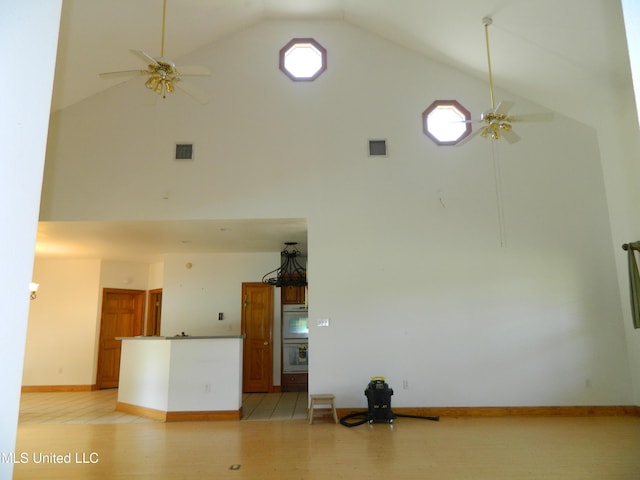 unfurnished living room with a ceiling fan and high vaulted ceiling