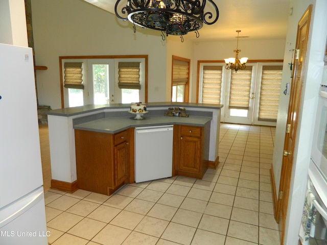 kitchen featuring brown cabinetry, a wealth of natural light, a notable chandelier, and white appliances