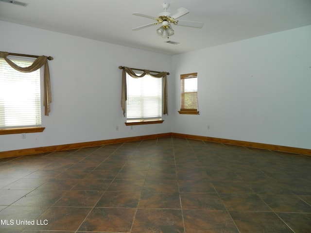 spare room with a ceiling fan, baseboards, and a wealth of natural light