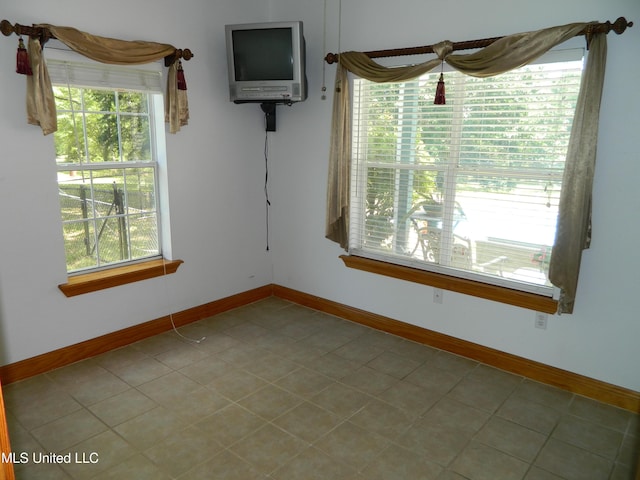 spare room with tile patterned flooring and baseboards