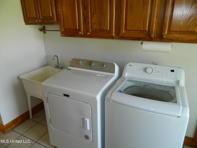 laundry room with washing machine and dryer, baseboards, light tile patterned flooring, and cabinet space