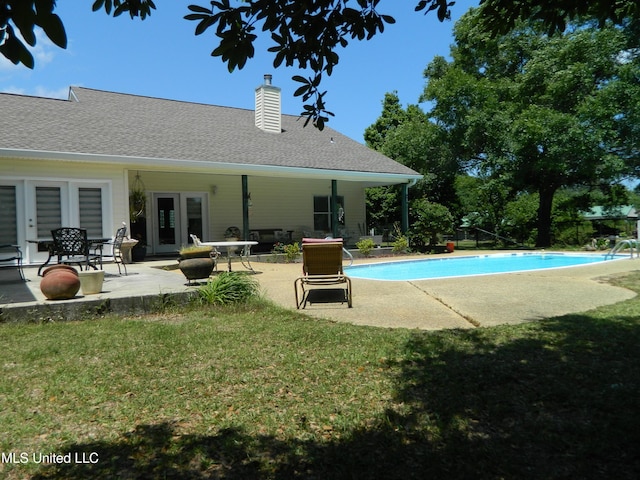 view of pool featuring a lawn, a patio area, a fenced in pool, and french doors