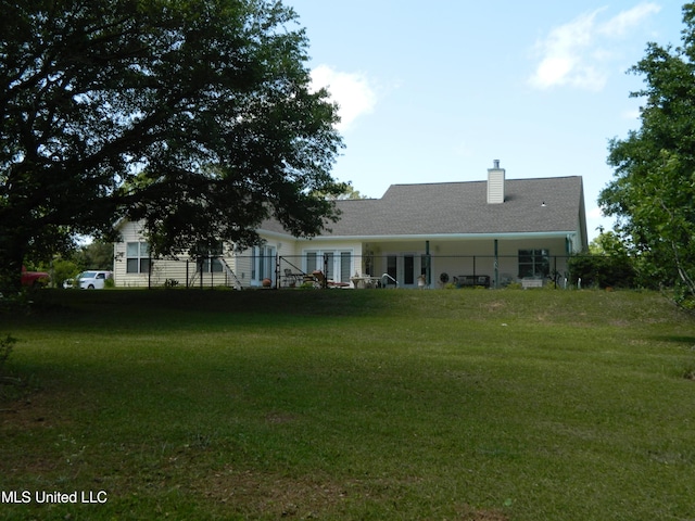 back of house with fence, a lawn, and a chimney