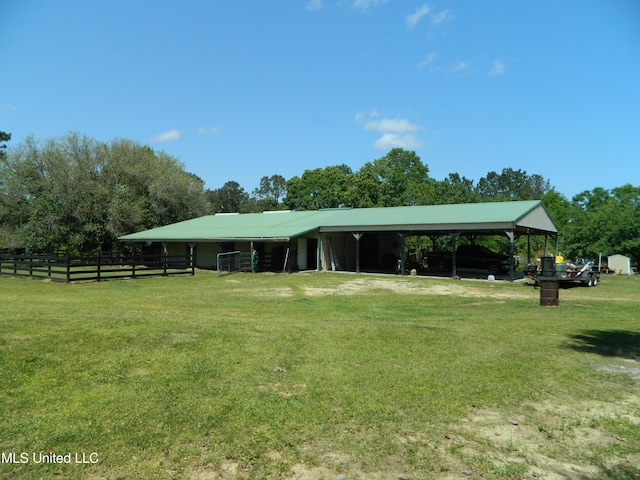 view of community with a lawn, fence, an outbuilding, and a carport