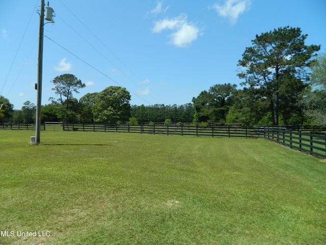 view of yard with fence and a rural view
