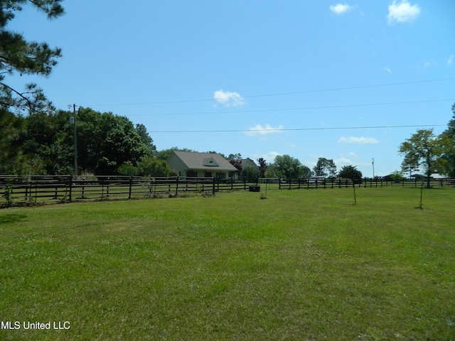 view of yard with fence and a rural view