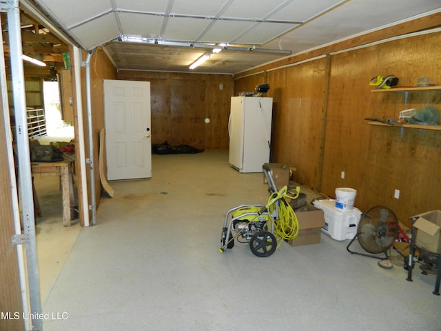 below grade area featuring freestanding refrigerator, wood walls, and a garage