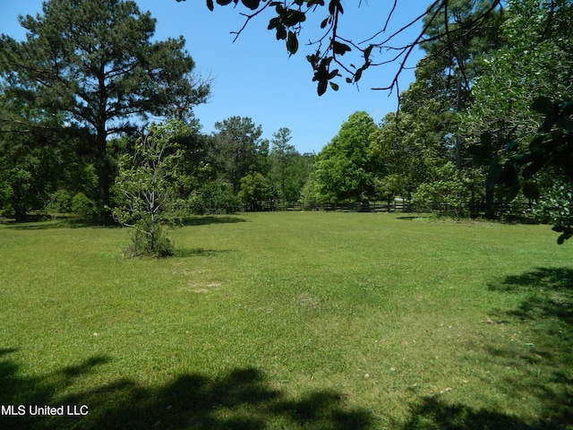 view of yard featuring a wooded view and fence