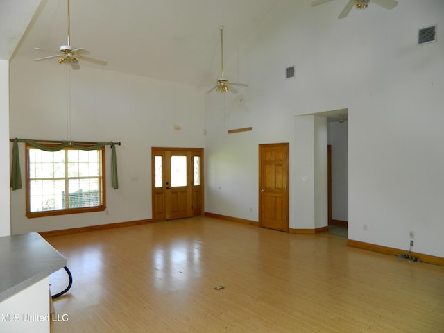 unfurnished living room with light wood finished floors, a ceiling fan, visible vents, and high vaulted ceiling