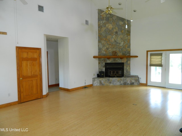 unfurnished living room featuring visible vents, baseboards, wood finished floors, a high ceiling, and ceiling fan