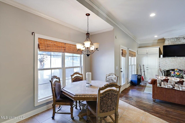 dining room featuring tile patterned flooring, ornamental molding, a chandelier, and a fireplace