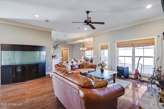 living room featuring a wealth of natural light, crown molding, ceiling fan with notable chandelier, and hardwood / wood-style flooring