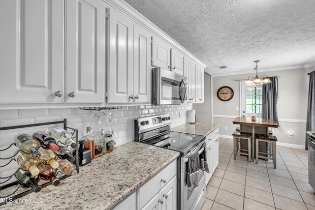 1201 Arbor Hill Dr, Brandon, MS 39042 - kitchen with stainless steel appliances, light tile patterned floors, white cabinetry, crown molding, and decorative backsplash
