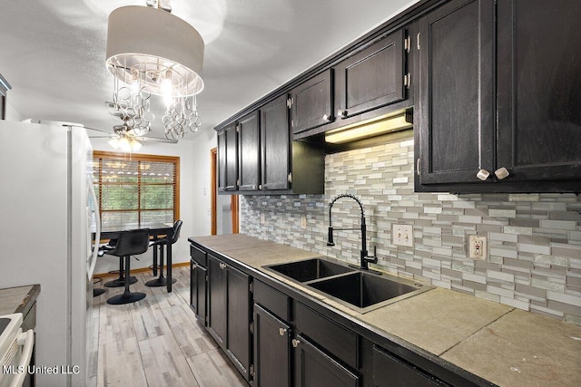 kitchen featuring tasteful backsplash, sink, pendant lighting, light hardwood / wood-style flooring, and white refrigerator