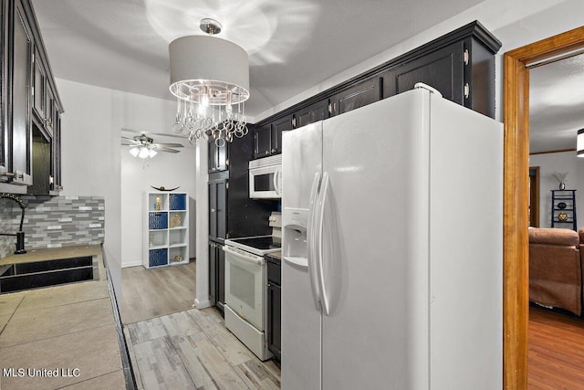 kitchen with decorative backsplash, white appliances, sink, pendant lighting, and light hardwood / wood-style floors