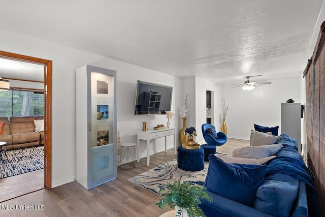 living room featuring light hardwood / wood-style floors, a textured ceiling, and ceiling fan