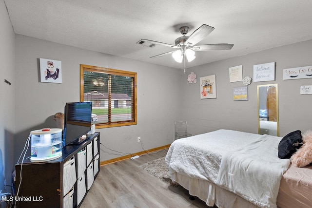 bedroom with light hardwood / wood-style floors, a textured ceiling, and ceiling fan