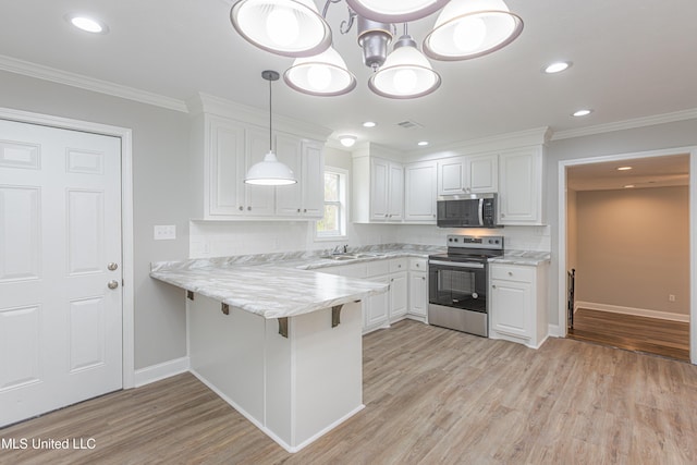 kitchen featuring appliances with stainless steel finishes, a breakfast bar, decorative light fixtures, white cabinetry, and kitchen peninsula