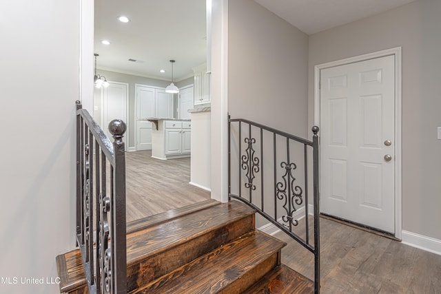 staircase with ornamental molding and hardwood / wood-style floors