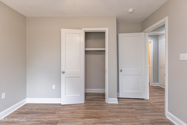 unfurnished bedroom with a closet and light wood-type flooring