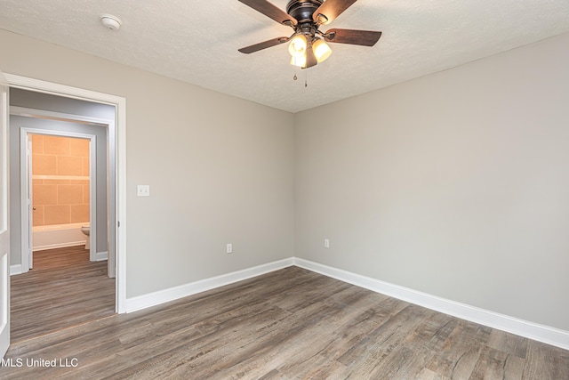 empty room with ceiling fan, dark hardwood / wood-style flooring, and a textured ceiling