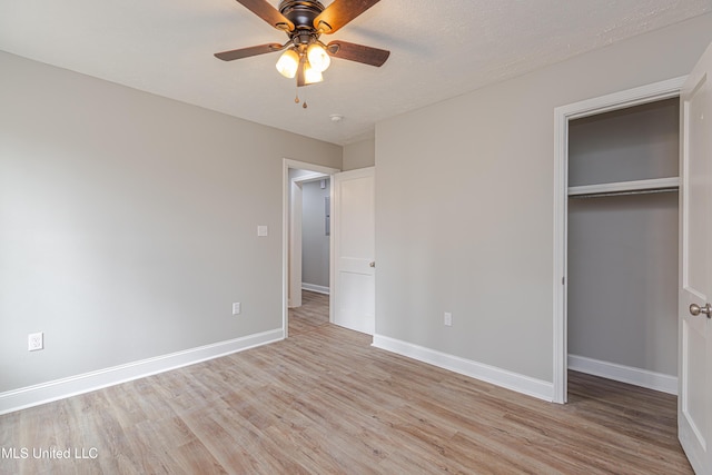 unfurnished bedroom featuring ceiling fan, a textured ceiling, a closet, and light wood-type flooring