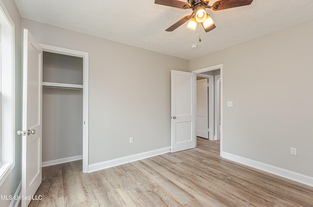 unfurnished bedroom featuring ceiling fan, a textured ceiling, a closet, and light wood-type flooring