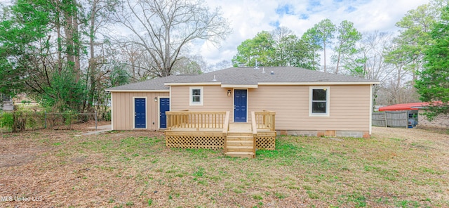 rear view of property featuring a wooden deck and a lawn