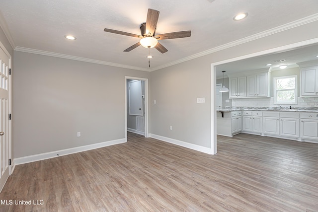 unfurnished living room featuring ornamental molding, ceiling fan, and light hardwood / wood-style floors